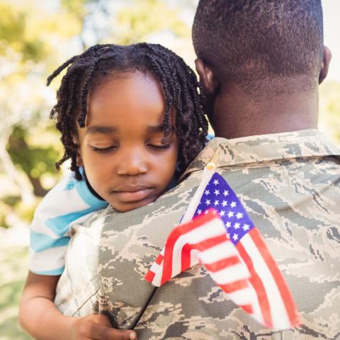 A small child is held by an adult in uniform.